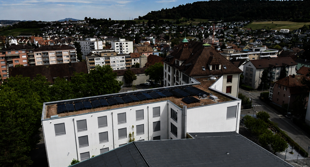 Detailansicht der Solarmodule auf dem begrünten Flachdach des Schulhauses Kirchacker mit angrenzendem Schulareal in Neuhausen.