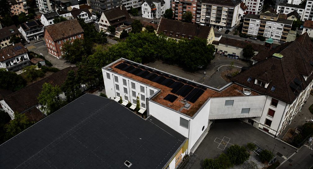 Luftaufnahme der 54-kWp-Photovoltaikanlage auf dem Schulhaus Kirchacker in Neuhausen am Rheinfall, geplant und realisiert durch reasco.immo.